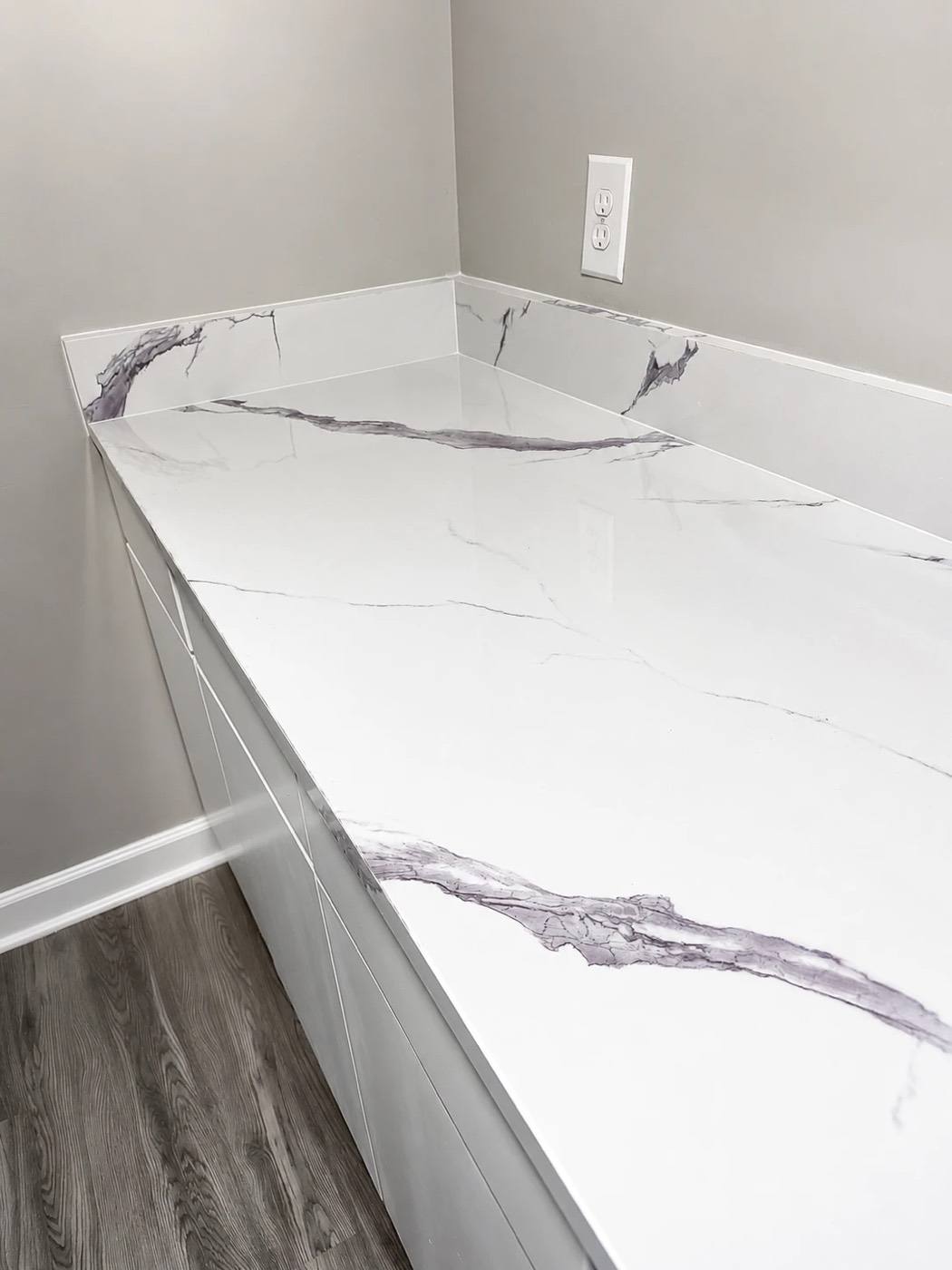 A renovated kitchen with quartz-look counters and white cabinets